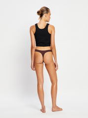 מבט מהגב על חוטיני ללא תפרים - ספיגה קלה בצבע Cocoa Brown, המציג כיסוי ישבן מינימלי. מידת הדוגמנית: XS