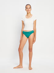 דוגמנית עומדת במבט חזיתי ולובשת תחתוני מחזור דגם מודיקומפורט ביקיני נערות. מידת הדוגמנית: Youth Small