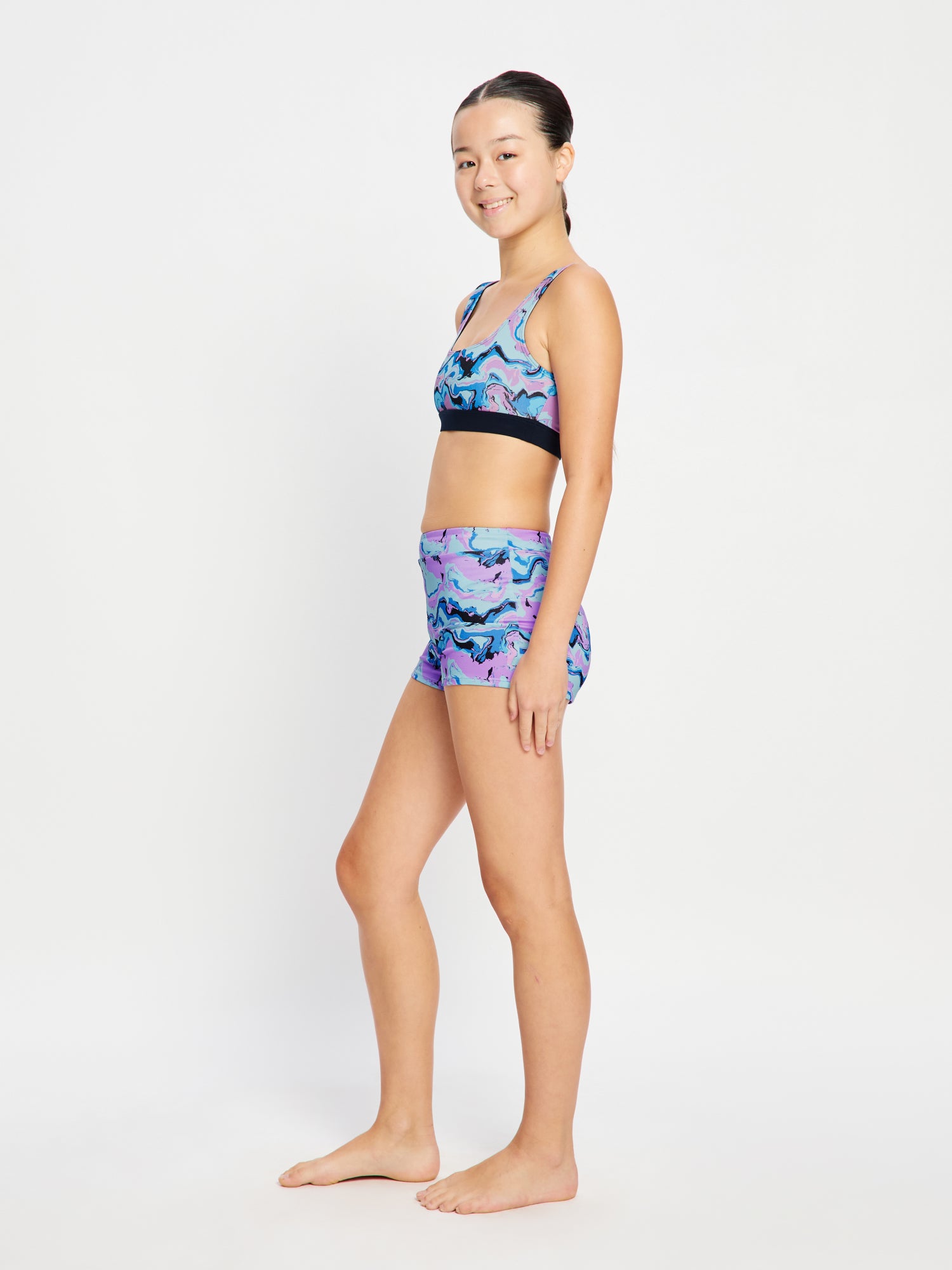 טופ בגד ים לנערות במבט מהצד (NVMS), מציג התאמה נוחה ומחטבת לגוף הנשי הצומח. מידת הדוגמנית- 10-12.