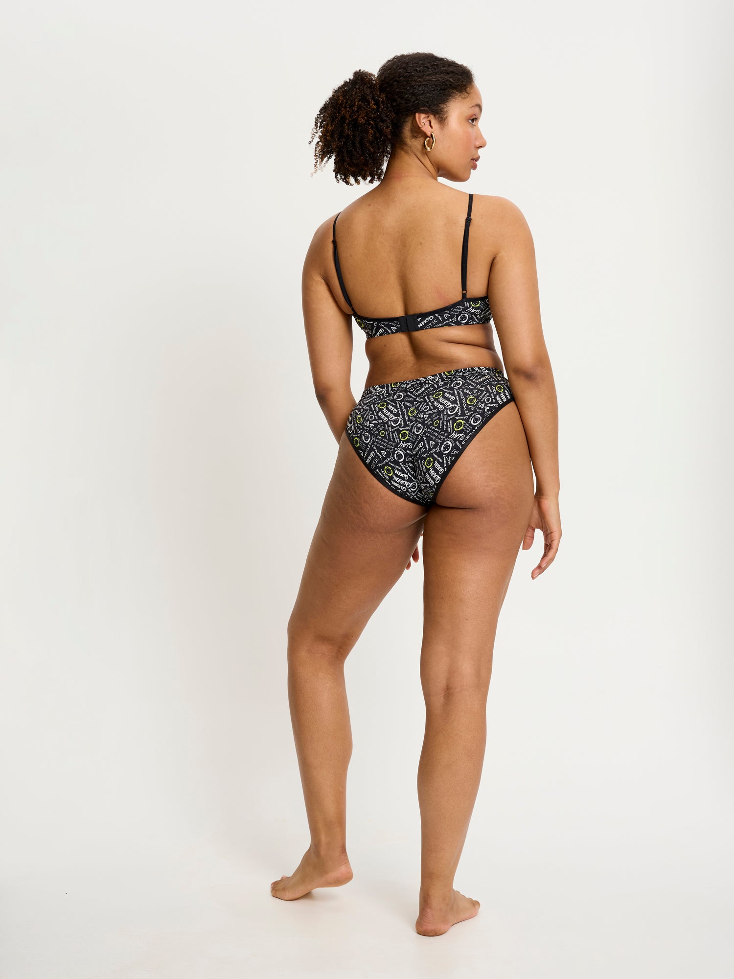 דוגמנית לובשת תחתון צ'יקי בריף מקולקציית סמיילי-וורלד, מבט מאחור המציג את המותן האלסטית החלקה. מידת הדוגמנית: L