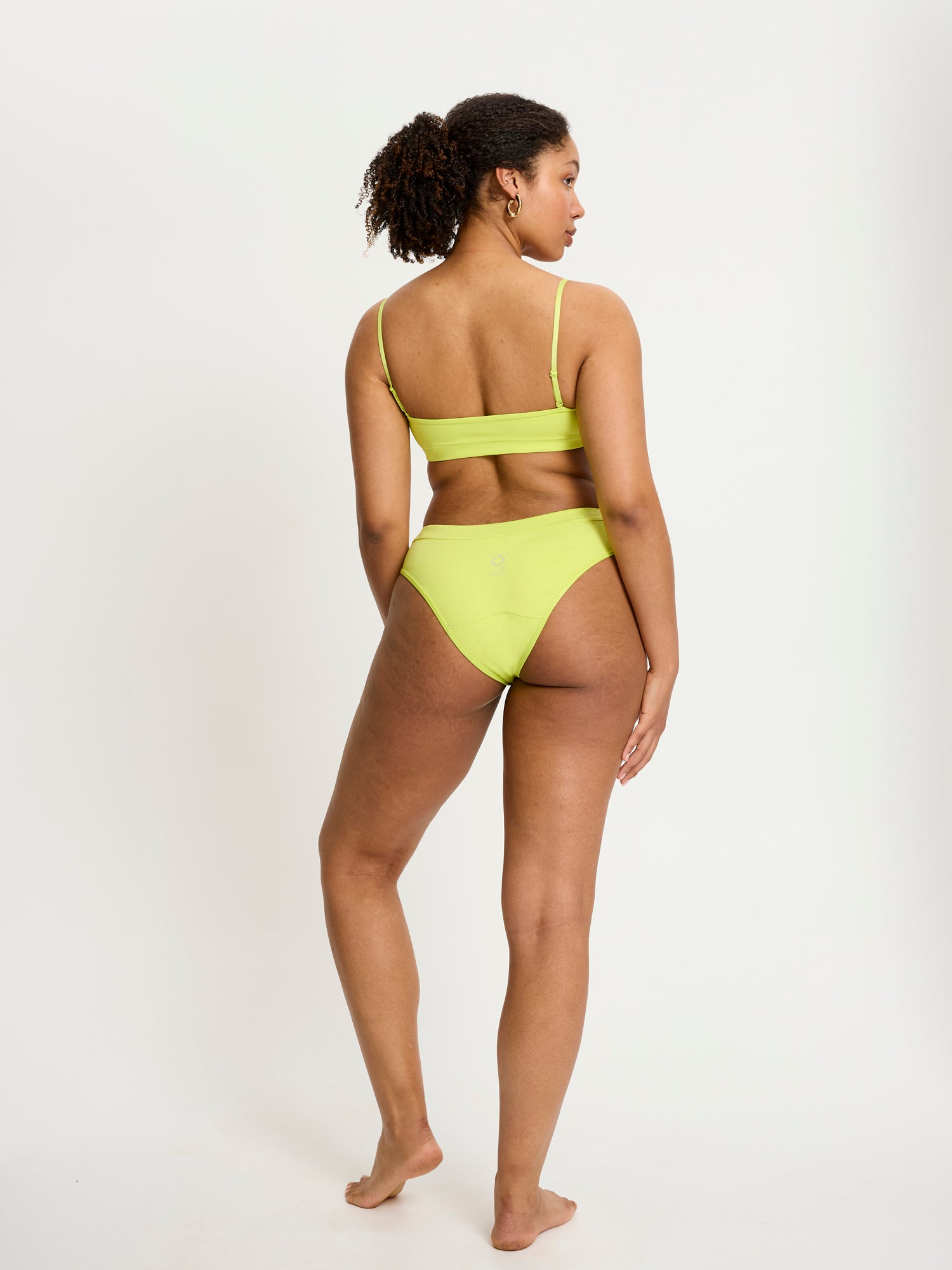 דוגמנית לובשת תחתון צ'יקי בריף מקולקציית סמיילי-וורלד, מבט מאחור המציג את הגזרה החלקה. מידת הדוגמנית L