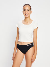 דוגמנית עומדת במבט חזיתי ולובשת תחתוני מחזור דגם מודיקומפורט ביקיני נערות בצבע שחור. מידת הדוגמנית: Youth Small